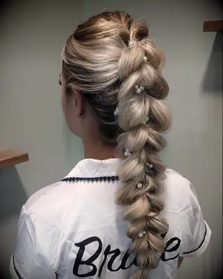 Bride with pull through braided ponytail with pearl accents wedding hairstyle