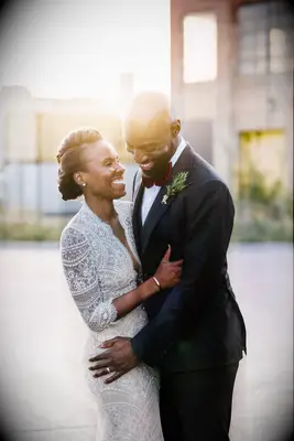 Bride with braided faux hawk smiling and hugging groom