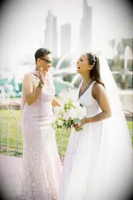 Mother and bride laugh while posing for the camera. 