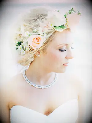 Messy wedding updo with a flower crown made with roses and daises