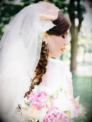 Curled wedding hairstyle with a floral hair accessory and veil