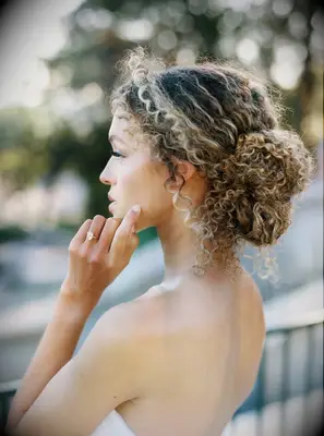Soft low bun with natural curls bridesmaid hairstyle