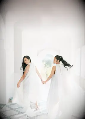 Two brides, one with a ponytail and one with hair down