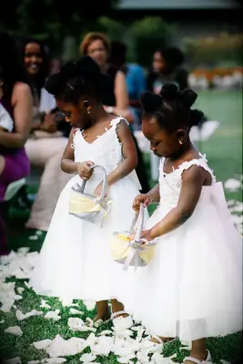 Flower girls wear their hair in funky updos while sprinkling rose petals on the aisle. 
