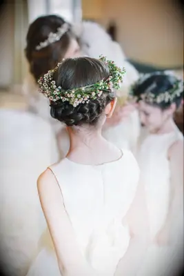 Flower girl wears her hair in a braided updo with a flower crown. 