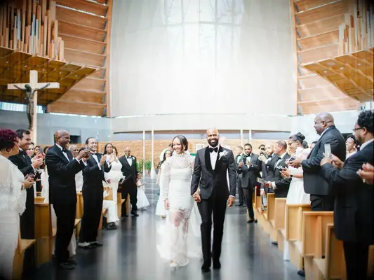 bride and groom hold hands and walk down the aisle during wedding recessional at church