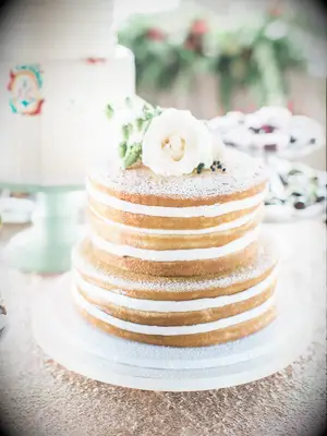 simple two tier naked wedding cake decorated with powdered sugar and white flower