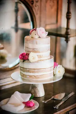 two tier semi naked wedding cake with pink peonies and white ranunculus