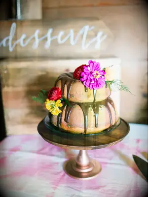 two tier bundt cake with chocolate drip glaze and purple, red and yellow flowers