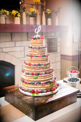 tall six tier naked wedding cake decorated with blueberries, raspberries and strawberries