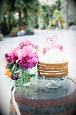 simple one tier naked wedding cake with flamingo topper making the shape of a heart between their beaks