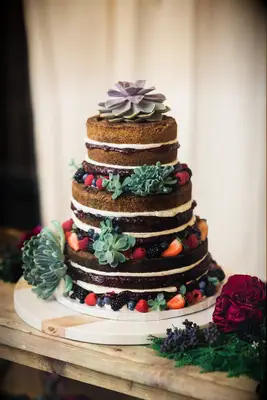 three tier chocolate naked wedding cake decorated with green and purple succulents and fresh berries