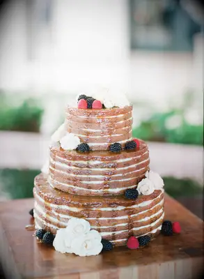 three tier naked wedding cake with sugar drip glaze icing, white roses and fresh blackberries and raspberries