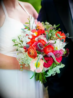 A bright wedding bouquet with dahlias, ranunculus, poppies and veronica