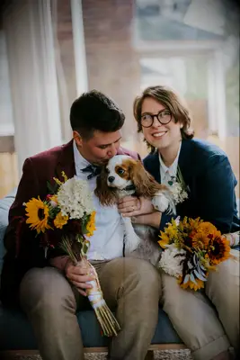 Couple posing with dog and sunflower bouquets