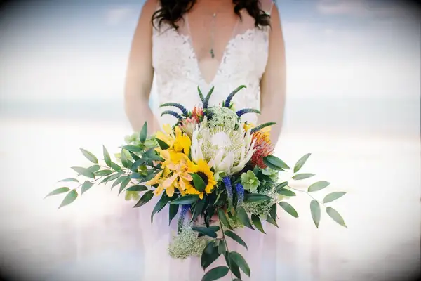 Bride holding sunflower bouquet on beach