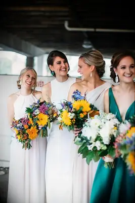 Bridesmaids holding colorful sunflower bouquets