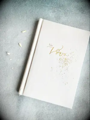 ivory velvet wedding vow book embossed with his vows written in gold lettering