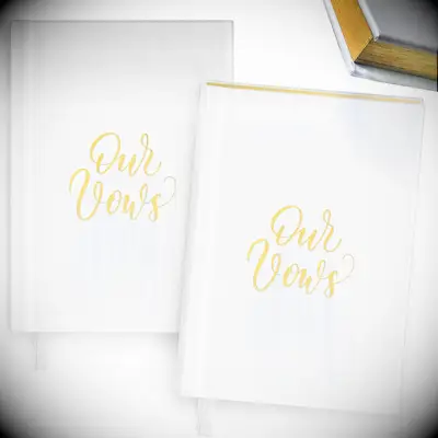 plain white hardcover vow books with our vows written in gold lettering on the front