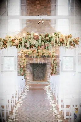 indoor wedding ceremony with hanging flower centerpiece and matching wedding fireplace decor