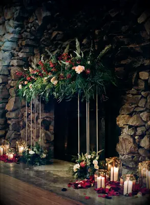 winter wedding fireplace decor with greenery and red flowers