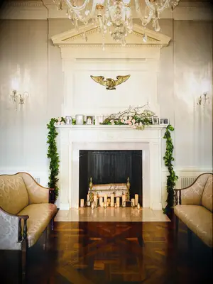 classic wedding fireplace decor idea with greenery garland and framed family photos along the mantel