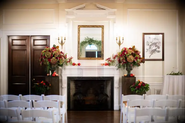 fall wedding fireplace decor with brown hydrangeas, red roses and red apples decorating the mantel