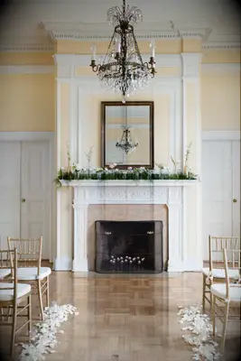 elegant wedding fireplace decor with greenery and fresh flowers in small glass bud vases along the mantel