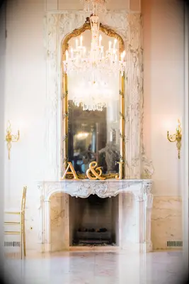 ornate marble wedding fireplace decorated with gold mirror and gold initial letters