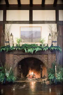 winter wedding fireplace decor idea with evergreens, wooden logs and blue tartan ribbon decorating the mantel
