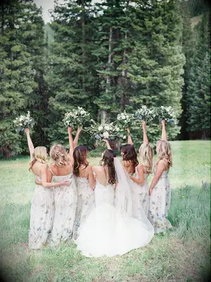 Photo of bridesmaids and bride holding bouquets in the air outside