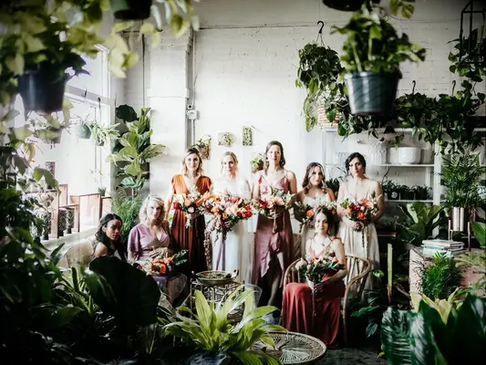Bridesmaids posing in tree nursery with bride