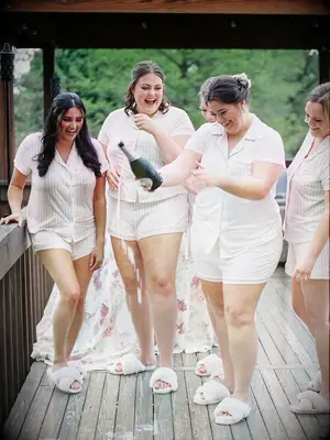 Bridesmaids and bride popping champagne on wedding morning
