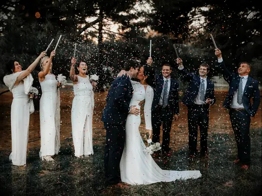 Bridesmaids and groomsmen tossing confetti over bride and groom