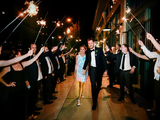 Bride and groom exiting wedding reception under sparkler tunnel