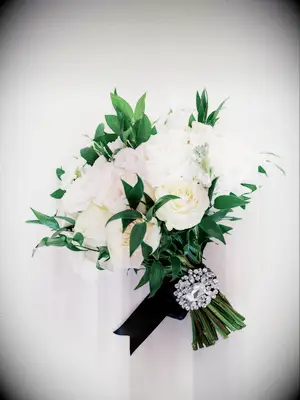 classic winter wedding bouquet with white roses decorated with black ribbon and silver rhinestone brooch on the stems