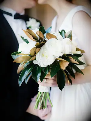 timeless winter wedding bouquet with white peonies and magnolia leaves