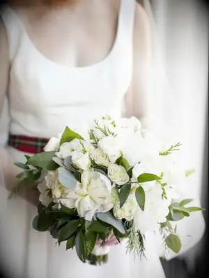 bride holding classic winter wedding bouquet with white roses and greenery