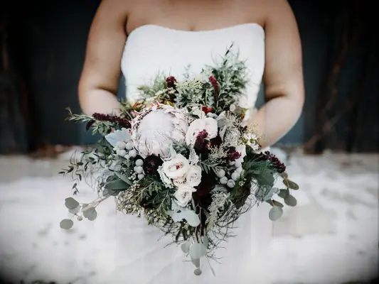 modern winter wedding bouquet with king protea, silver brunia, burgundy flowers, blush roses and greenery