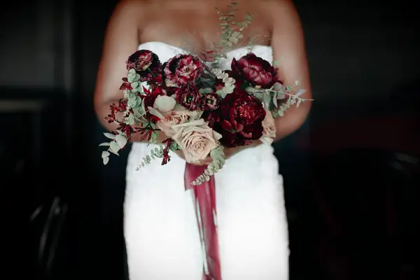 bride holding burgundy winter wedding bouquet