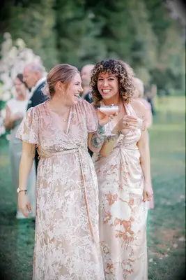 Two wedding guests smiling with drinks in hand