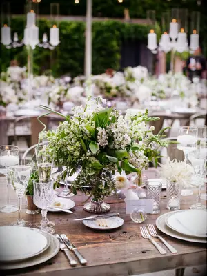 short greenery centerpiece in silver compote vase with white wax flowers and lily of the valley