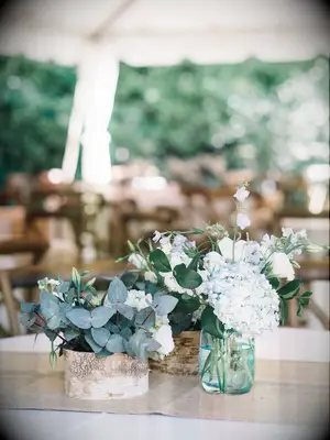 short rustic wedding centerpieces with eucalyptus, blue hydrangeas and wooden vessels
