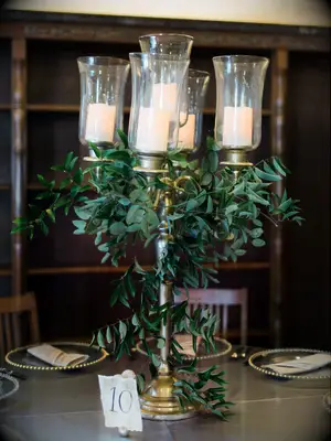 wedding centerpiece with gold candelabra decorated in greenery vines