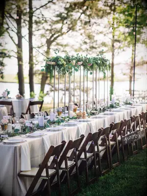 long outdoor wedding reception table with mixed high and low greenery centerpieces