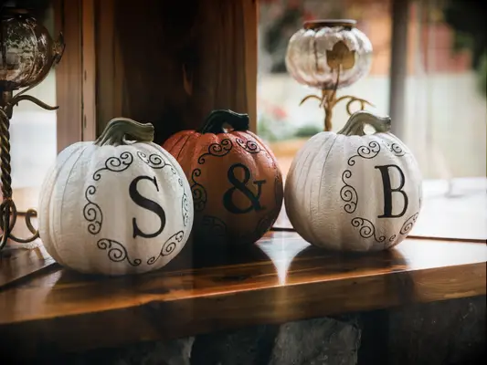 white and orange pumpkins decorated with ampersand and couple