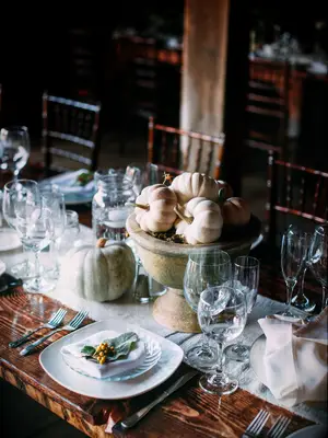 fall wedding tablescape with mini orange and green pumpkins in stone urn