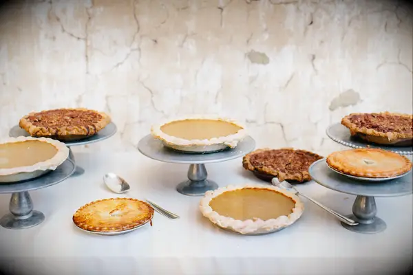 fall wedding dessert table with pumpkin pies and apple pies on silver cake stands