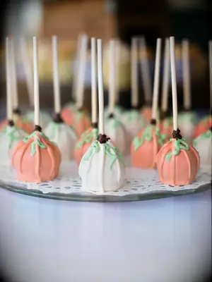 tray of orange and white cake pops decorated like miniature pumpkins
