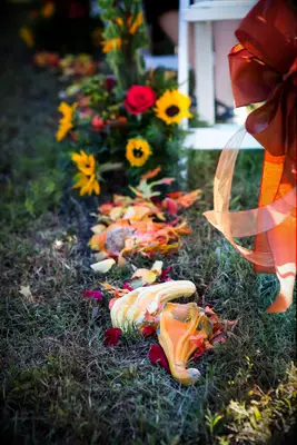 pumpkin wedding decor idea orange and yellow gourds with red rose petals scattered along the ceremony aisle